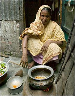 woman sitting next to cooking stove with pots of food