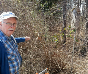 Bill Willis pointing to a butterfly house